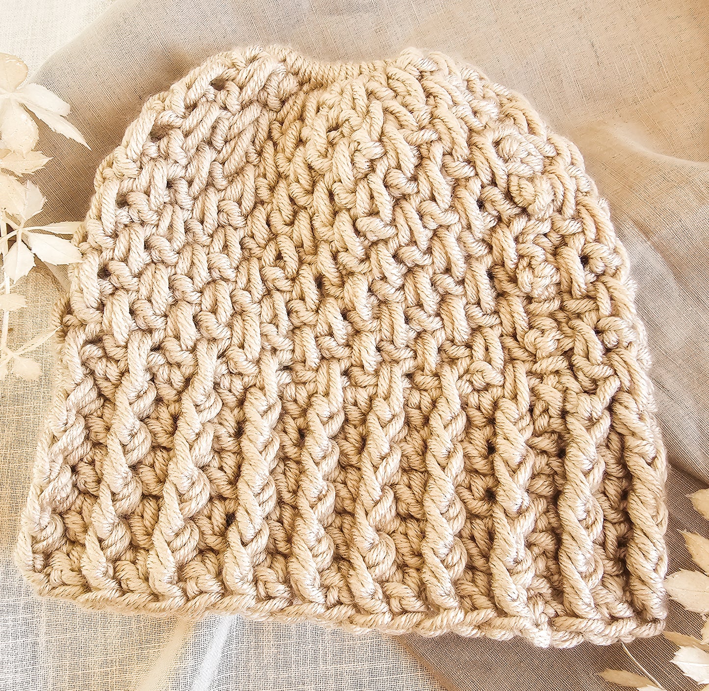 Beige knitted hat on a textured fabric background