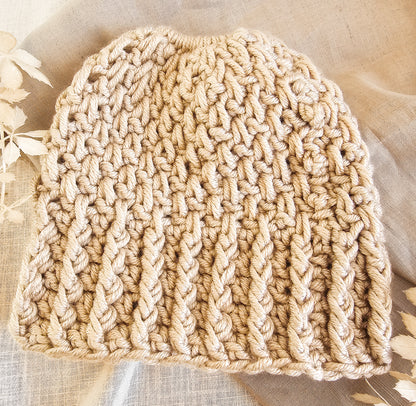 Beige knitted hat on a textured fabric background